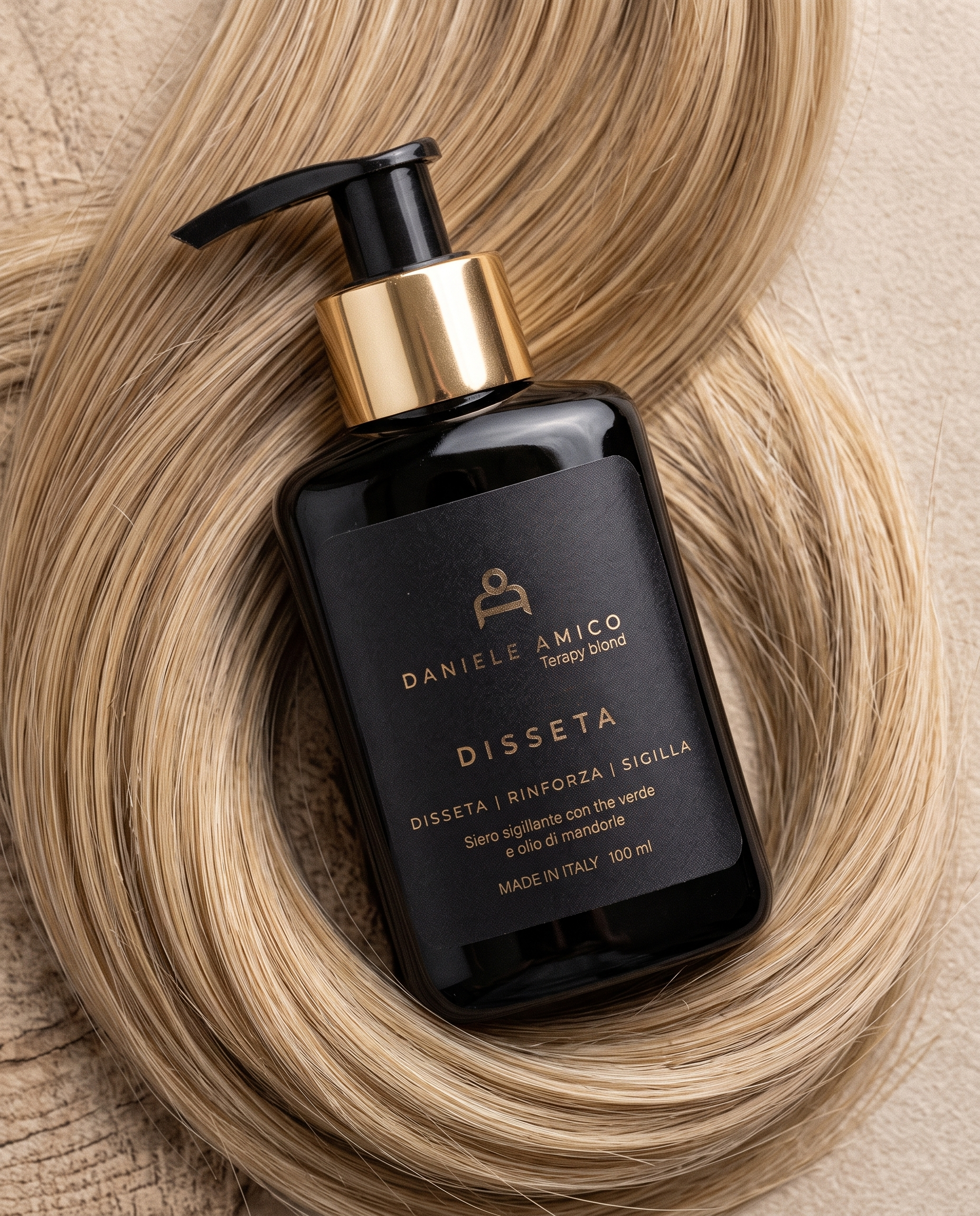 Disseta, siero sigillante Terapy Blond per capelli biondi, flacone nero con pompa dorata su una ciocca di capelli biondi