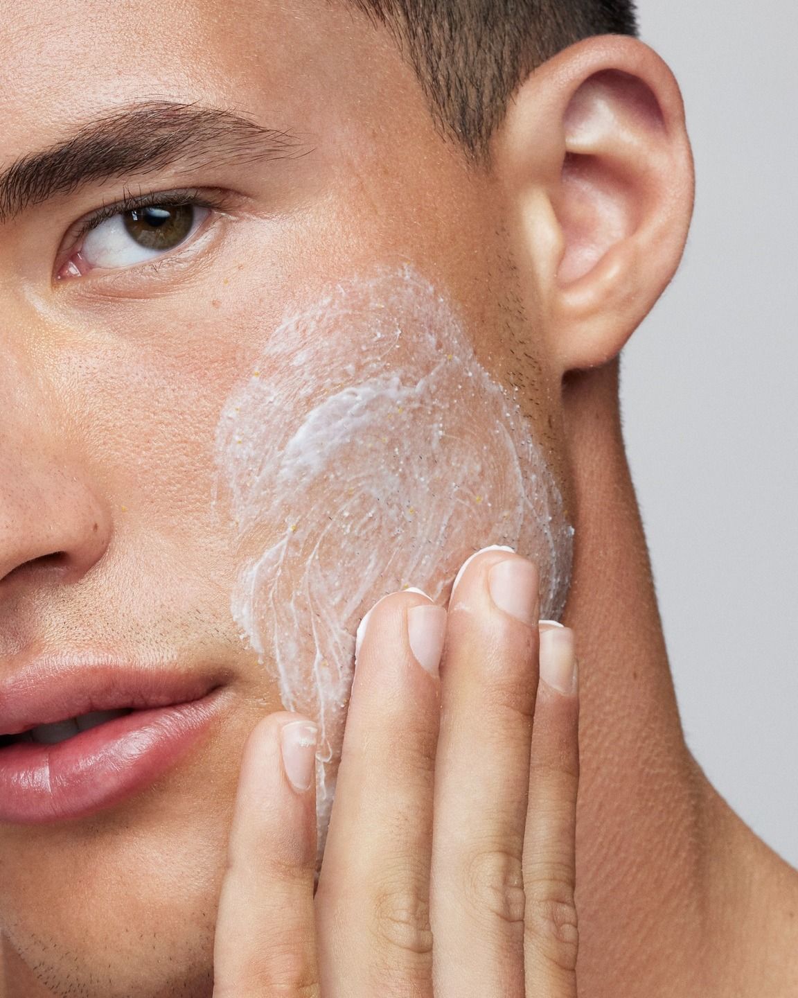 Primo piano di un uomo che applica la crema Raso sulla guancia